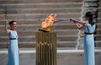 L'actrice grecque Xanthi Georgiou, habillée en grande prêtresse de la Grèce antique, allume la torche olympique sous le regard de la chorégraphe Artemis Ignatiou lors de la remise de la flamme olympique.