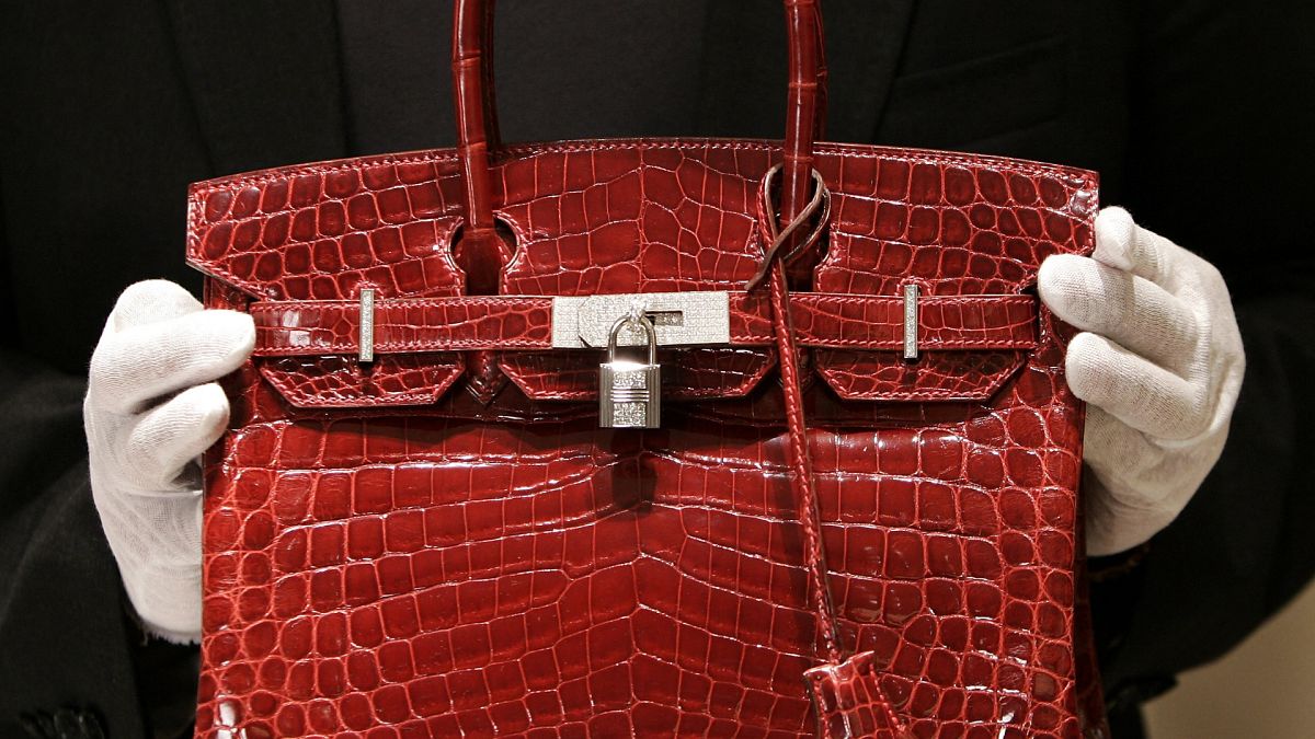 A employee holds a 129,000 USD crocodile Hermes Birkin Bag for the press to see during a private opening for the new Hermes store on Wall Street in New York 21 June 2007.