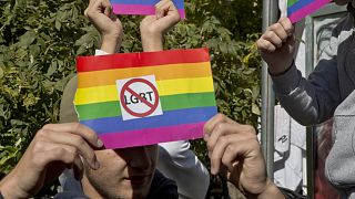 Grupos anti-LGBT seguram uma bandeira arco-íris com autocolantes anti-LGBT durante o primeiro desfile do Orgulho Gay do Kosovo em 2017.
