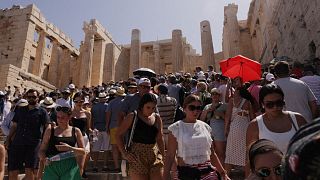 Visitantes caminan frente a los Propileos de la Acrópolis, durante una ola de calor en Atenas, Grecia, 14 de julio de 2023\.