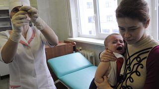 A medical worker prepares to administer a vaccine to 16 month old Yaroslav who is being held my his mother Oksana in Ukraine, 2009.