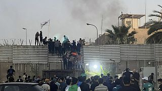 متظاهرون يتسلقون جداراً في السفارة السويدية في بغداد، 20 يوليو 2023. 