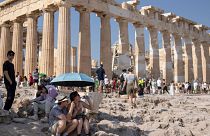 Tourist sit in front of the five century BC Parthenon temple at the Acropolis hill during a heatwave, Thursday 13 July 2023.