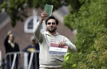 Salwan Momika, behind Sunday's protest, holds up the Muslim holy book the flag of Iraq during a protest outside the Iraqi Embassy in Stockholm, Sweden, in July