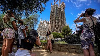People take pictures in front of Sagrada Familia Basilica designed by architect Antoni Gaudi in Barcelona, Spain