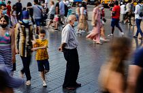A man wearing a face mask to protect against the spread of coronavirus pauses as people walk along a street in downtown Barcelona, Spain, July 3, 2021.