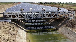 Trabalhadores indianos dão os últimos retoques em painéis solares instalados que cobrem o canal de Narmada na aldeia de Chandrasan, nos arredores de Ahmadabad, Índia, abril de 2012\.
