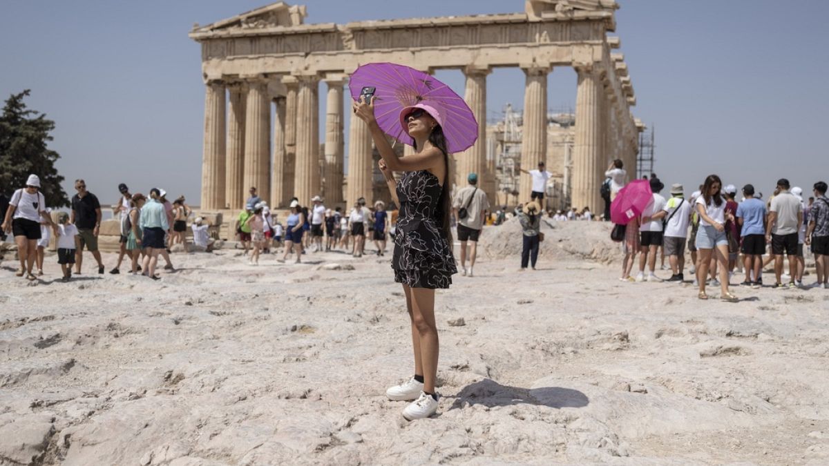 FILE - A woman takes a selfie in front of Parthenon temple atop of the ancient Acropolis hill during a heat wave in Athens, Greece, Friday, July 21, 2023. 