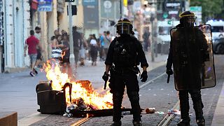 ضباط شرطة مكافحة الشغب الفرنسية يقفون حراسة بجوار صندوق قمامة محترق خلال مظاهرة ضد الشرطة في مرسيليا ، جنوب فرنسا في 1 يوليو 2023.
