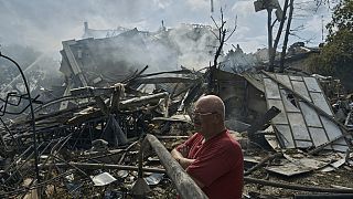A man watches as emergency service personnel work at the site of a destroyed building after a Russian attack in Odesa, Ukraine, Thursday, July 20, 2023.