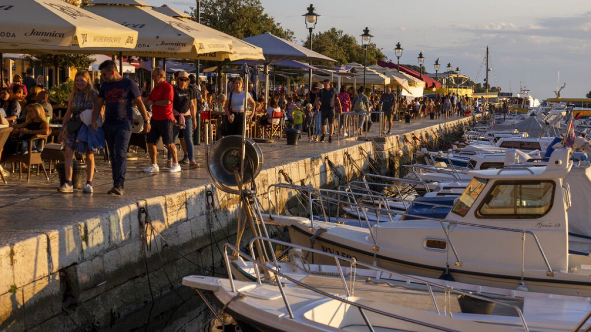 Holidaymakers walk by the harbor, in the Adriatic town of Rovinj, Croatia