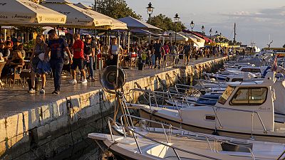 Holidaymakers walk by the harbor, in the Adriatic town of Rovinj, Croatia