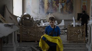 A boy helps salvage items at the Odesa Transfiguration Cathedral after it was heavily damaged in Russian missile attacks in Odesa, Ukraine, Sunday, July 23, 2023. 