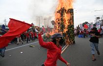Protesters run past a giant military boot after setting it up on fire as they march towards Congress for a demonstration in Quezon City, suburban Manila on July 24, 2023