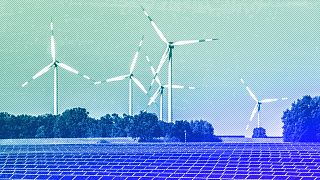 Wind turbines turn behind a solar farm in Rapshagen, October 2021
