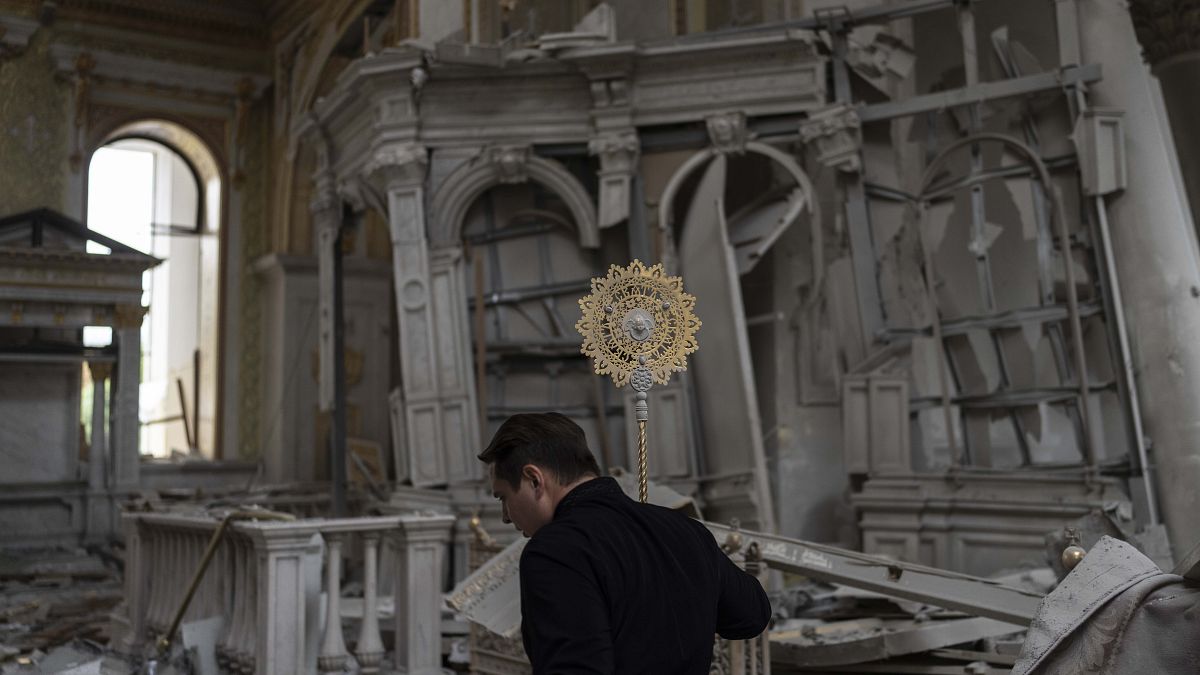 A church personnel salvages items while helping clean up inside the Odesa Transfiguration Cathedral after it was heavily damaged in Russian missile attacks in Odesa, Ukraine