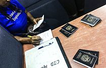  صورة من الارشيف- ضابط من الإنتربول يتحقق من جوازات السفر خلال مداهمة في النوادي الليلية في جورج تاون، غيانا.
