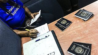  صورة من الارشيف- ضابط من الإنتربول يتحقق من جوازات السفر خلال مداهمة في النوادي الليلية في جورج تاون، غيانا.
