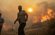 A local reacts as the flames burn trees in Gennadi village, on the Aegean Sea island of Rhodes, southeastern Greece, on Tuesday, July 25, 2023.