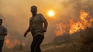 Un homme près d'un incendie sur l'île de Rhodes (25/07/2023)