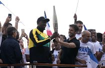 Usain Bolt (balra) és Torony Estanguet az olimpiai fáklyával Párizsban 2023.07.25-én