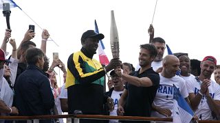 Usain Bolt (balra) és Torony Estanguet az olimpiai fáklyával Párizsban 2023.07.25-én