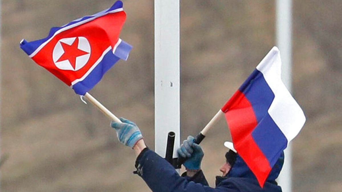 A worker adjusts the flag of Russia and North Korea along the road in Russky Island, off the southern tip of Vladivostok, Tuesday, April. 23, 2019