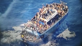 A görög parti őrség által 2023\. június 14-én rendelkezésre bocsátott, dátum nélküli képen több ember látható egy megrongálódott halászhajón, amely később felborult és elsüllyedt Görögországnál.