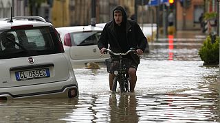 Egy férfi térdig érő vízben biciklizik Olaszországban
