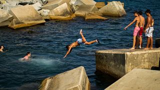 Молодые люди ныряют в Средиземное море в жаркий день в Барселоне, Испания, 21 июля 2022 года.
