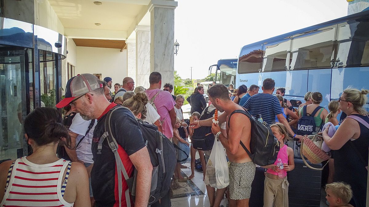 Evacuees wait to board on buses as they leave their hotel during a forest fire on the island of Rhodes, Greece