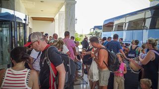 Evacuees wait to board on buses as they leave their hotel during a forest fire on the island of Rhodes, Greece