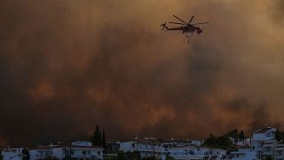 A helicopter operates over a wildfire burning in Gennadi village, on the Aegean Sea island of Rhodes, on 25 July 2023.