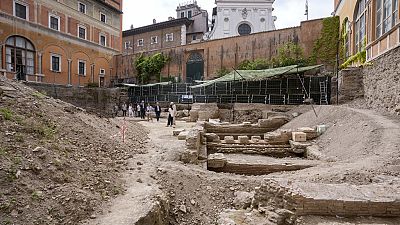People walk in the excavation site of the ancient Roman emperor Nero's theater, 1st century AD, backdropped by the church of Santo Spirito in Sassia, in Rome.