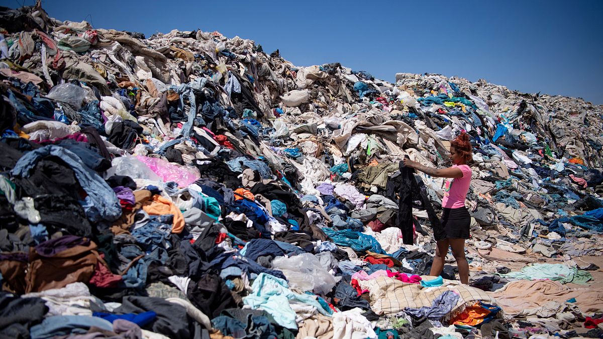 Una mujer busca ropa usada entre toneladas desechadas en el desierto de Atacama, Chile