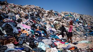 Eine Frau sucht in der Atacama-Wüste in Chile inmitten von weggeworfenen Textilien nach brauchbarer Kleidung