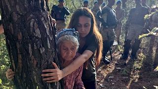 88-летняя Зехра Йылдырым обнимает дерево, чтобы защитить его от вырубки 26 июля. Ее прикрывает лидер активистов Эсра Ишик.