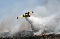 Um avião lança água sobre um incêndio florestal perto da cidade de Volos, no centro da Grécia, esta quinta-feira.