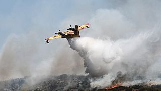 Самолёт пожарной авиации  сбрасывает воду на огонь возле города Волос в центральной Греции, 27 июля 2023 года.