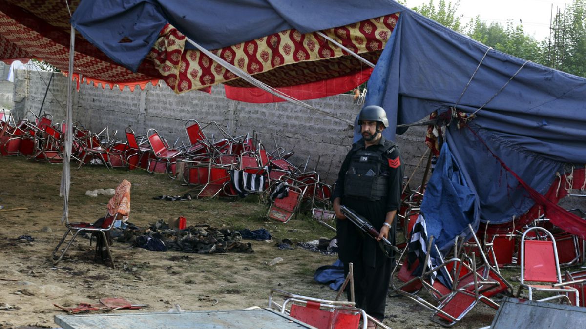 Agente da polícia paquistanesa vigia local onde bombista suicida se fez explodir, em Bajur, Paquistão