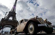 Car enthusiasts drive past the Eiffel tower during the 16th "Traversee estivale" vintage vehicles parade through Paris on July 30, 2023.