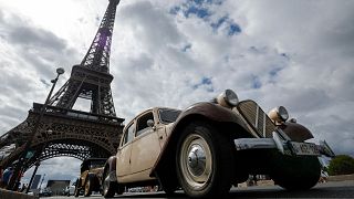 Car enthusiasts drive past the Eiffel tower during the 16th "Traversee estivale" vintage vehicles parade through Paris on July 30, 2023. 