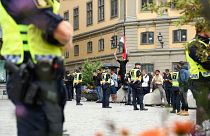 Policemen stand next to demonstrators, among them a protester (background, C) holding the flag of Iraq, at Mynttorget square in Stockholm, Sweden, on July 31, 2023.