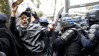 Riot police officers charge a man holding his phone during a protest rally in Paris, France