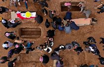نمایی هوایی از عزاداران در حال دفن اجساد قربانیان ایزدی کشته شده توسط داعش در قبرستانی در سنجار، عراق، ۲۰۲۱