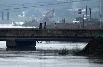 Люди идут по закрытому мосту, частично затопленному разлившейся рекой / Провинция Хэбэй, Китай.