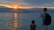 السياح يلتقطون صورًا أثناء غروب الشمس في مدينة نافبليون، جنوب اليونان، في 31 يوليو 2023.
