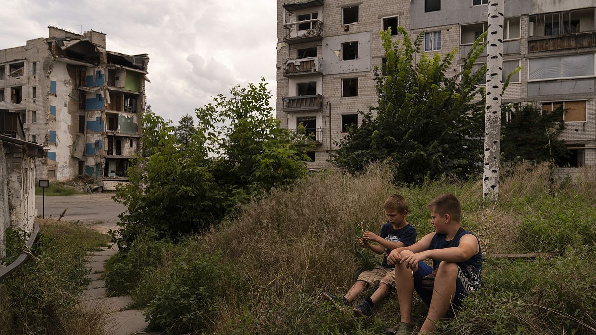 Dos niños pasan el tiempo cerca de edificios de apartamentos gravemente dañados por los ataques rusos en Borodyanka, Ucrania, el 2 de agosto de 2023.