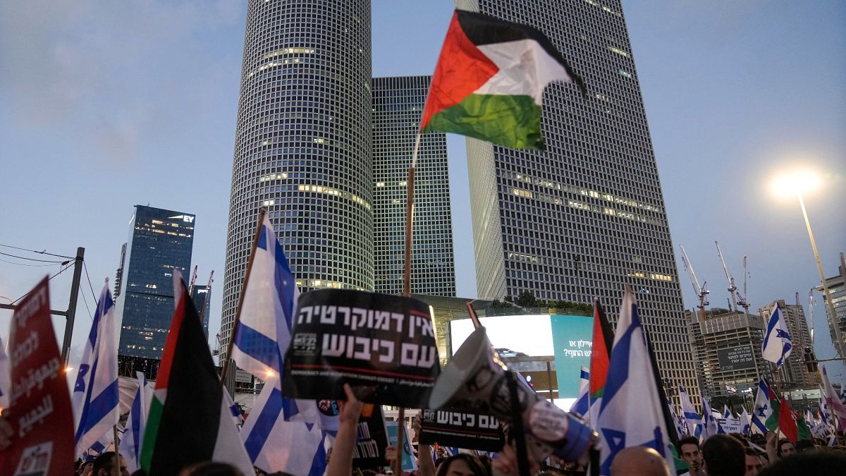 متظاهرون يلوحون بالعلمين الفلسطيني والإسرائيلي في تل أبيب 