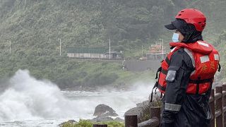 Oficial da guarda costeira observa as ondas antes da passagem do tufão Khanun, no norte de Taiwan, esta quinta-feira.